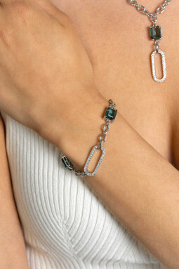 ZINZI zilveren fantasie schakel armband met ovale schakel, bezet met witte zirconia's en twee groenachtig blauwe (petrol) kleurstenen in vierpootszetting 18-21cm ZIA2487